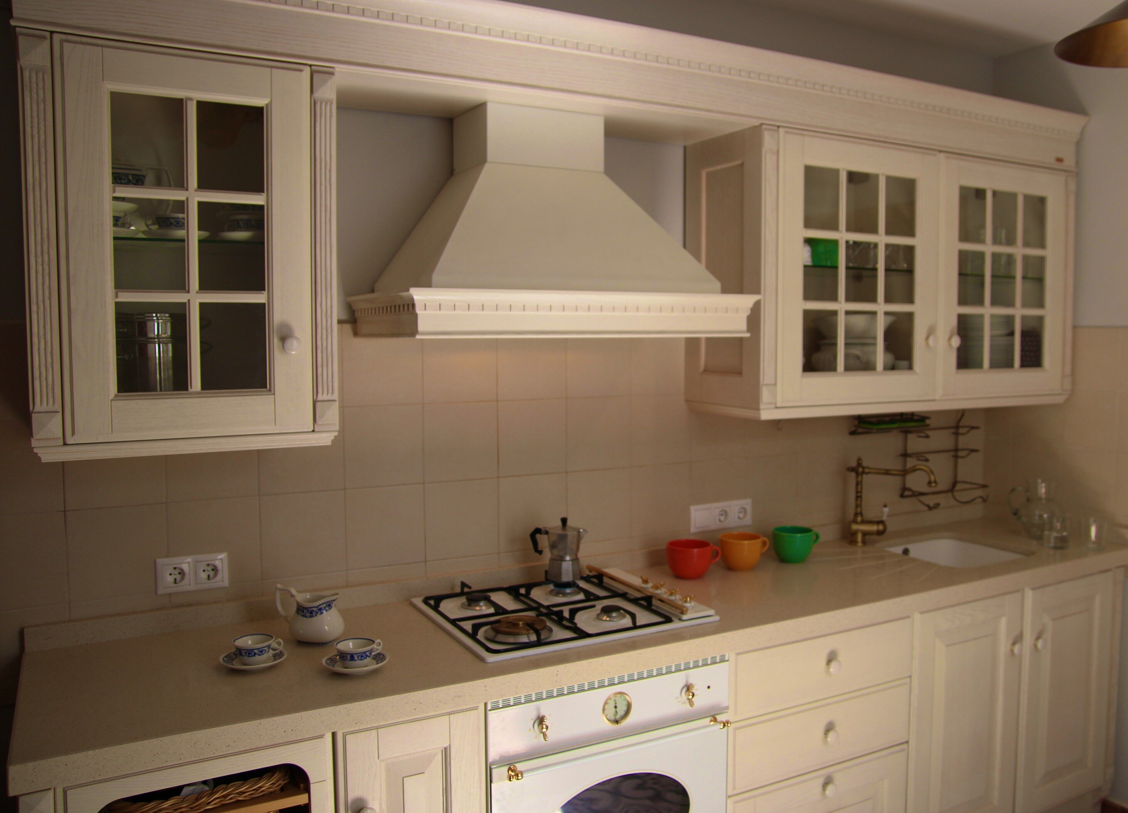 A kitchen with white cabinets, a gas stove, and a range hood.