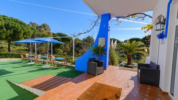 A covered outdoor area with a patio, seating, and a blue wall.