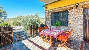 An outdoor patio with a stone table and wooden chairs, a wooden fence, and a stone wall. - El Secano de Paco Órgiva by Ruralidays (Granada)