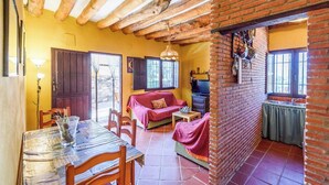 A cozy living area with a dining table, sofa, and a kitchen area with a brick wall. - El Secano de Paco Órgiva by Ruralidays (Granada)