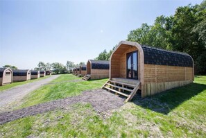 A row of wooden pod-style accommodations with a central entrance, each with a small porch.