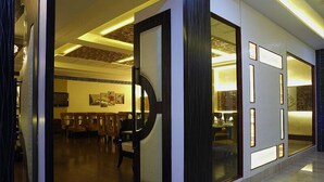 Un vestíbulo de hotel con una recepción, zona de estar y vistas al comedor.