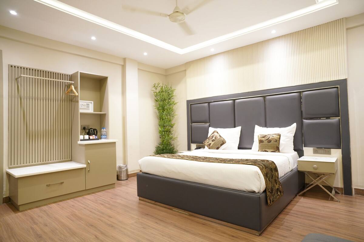 Quarto moderno com cama grande, mesas de cabeceira, guarda-roupa e ventoinha no teto.