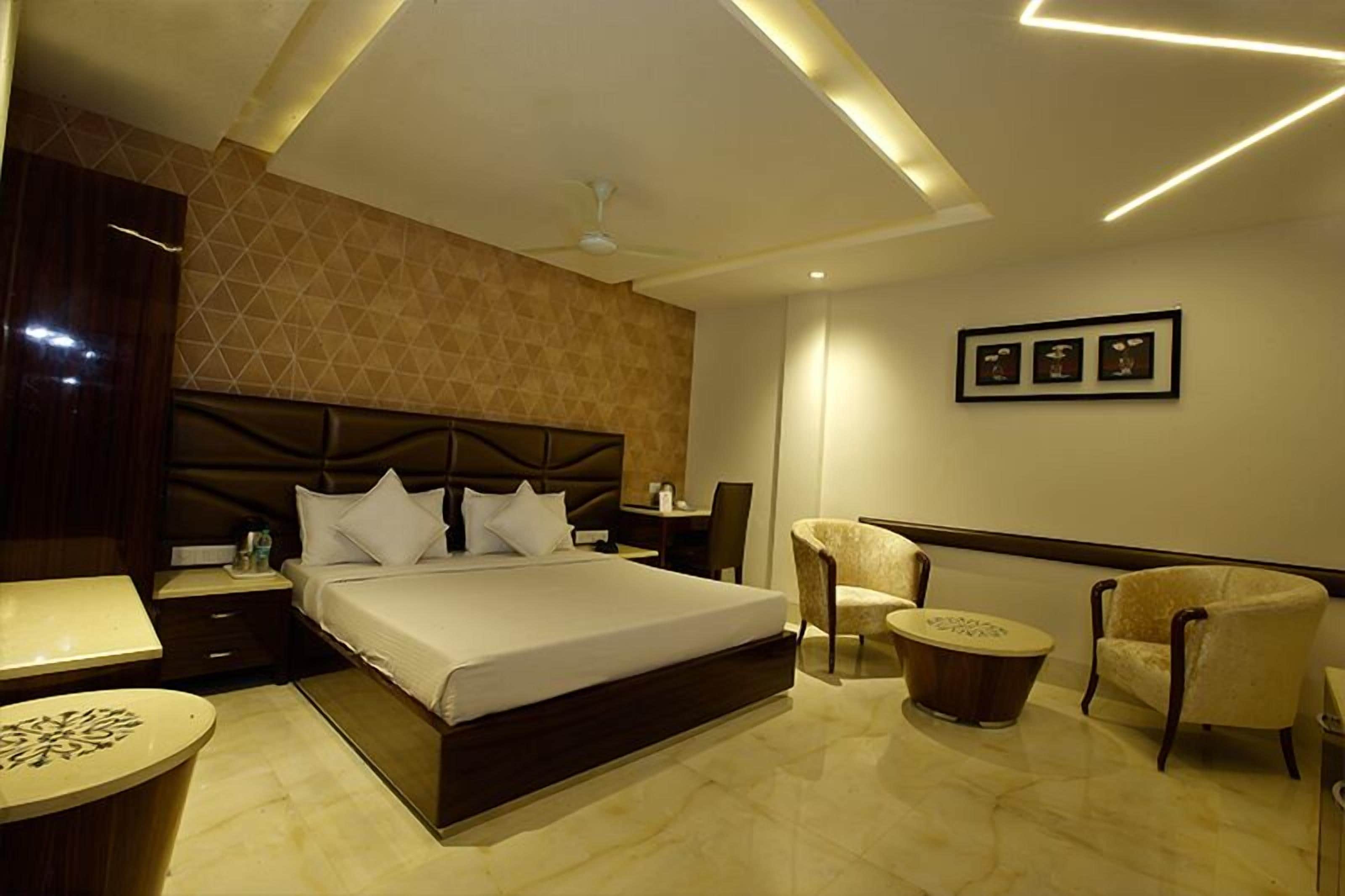 A modern hotel room with a large bed, a desk, a chair, and a small table.