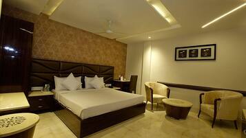 A modern hotel room with a large bed, a desk, a chair, and a small table.