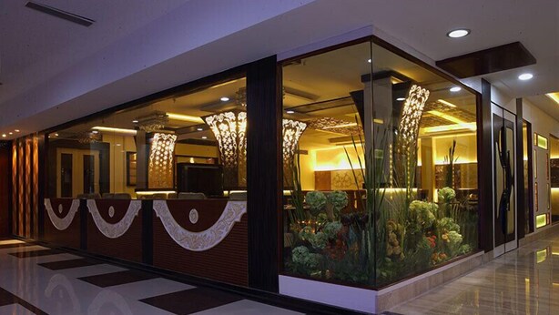 Un moderno vestíbulo de hotel con una recepción, separadores de vidrio e iluminación decorativa.
