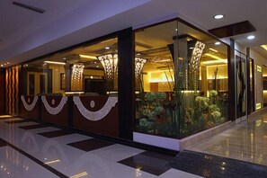 A modern hotel lobby with a reception desk, glass partitions, and decorative lighting. - Hotel Nagpal Regency (Ludhiana)