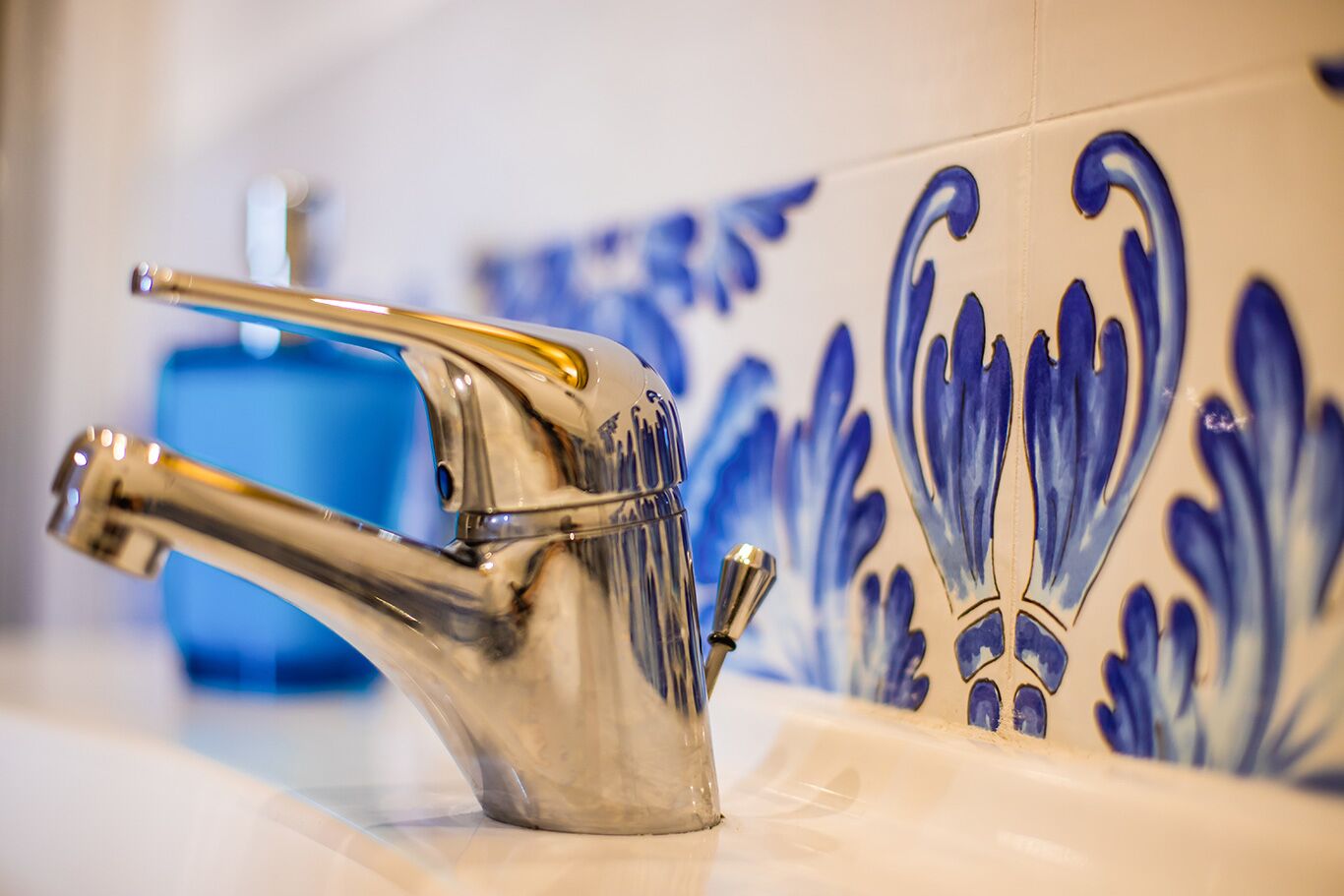 A modern bathroom with a chrome faucet and decorative blue tiles.