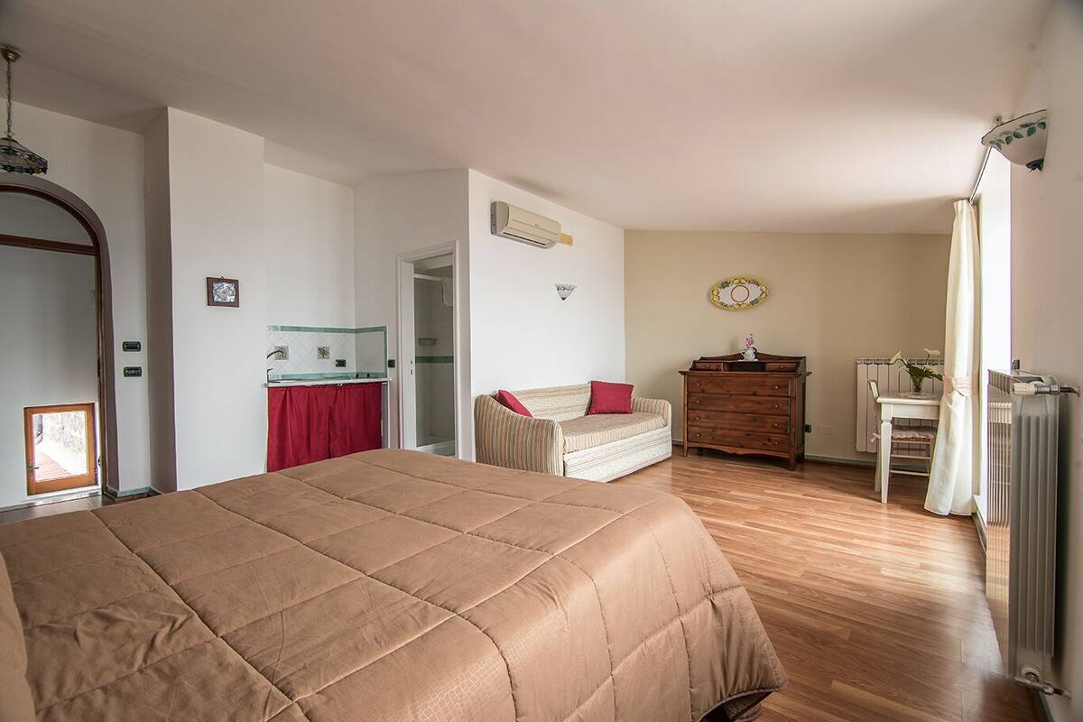 A bedroom with a large bed, a dresser, a chair, and a radiator.