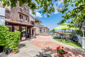 A courtyard with a stone building, potted plants, and outdoor furniture. - Agriturismo Il Giardino di Vigliano (Massa Lubrense)