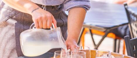 A person pouring water into glasses on a tray.