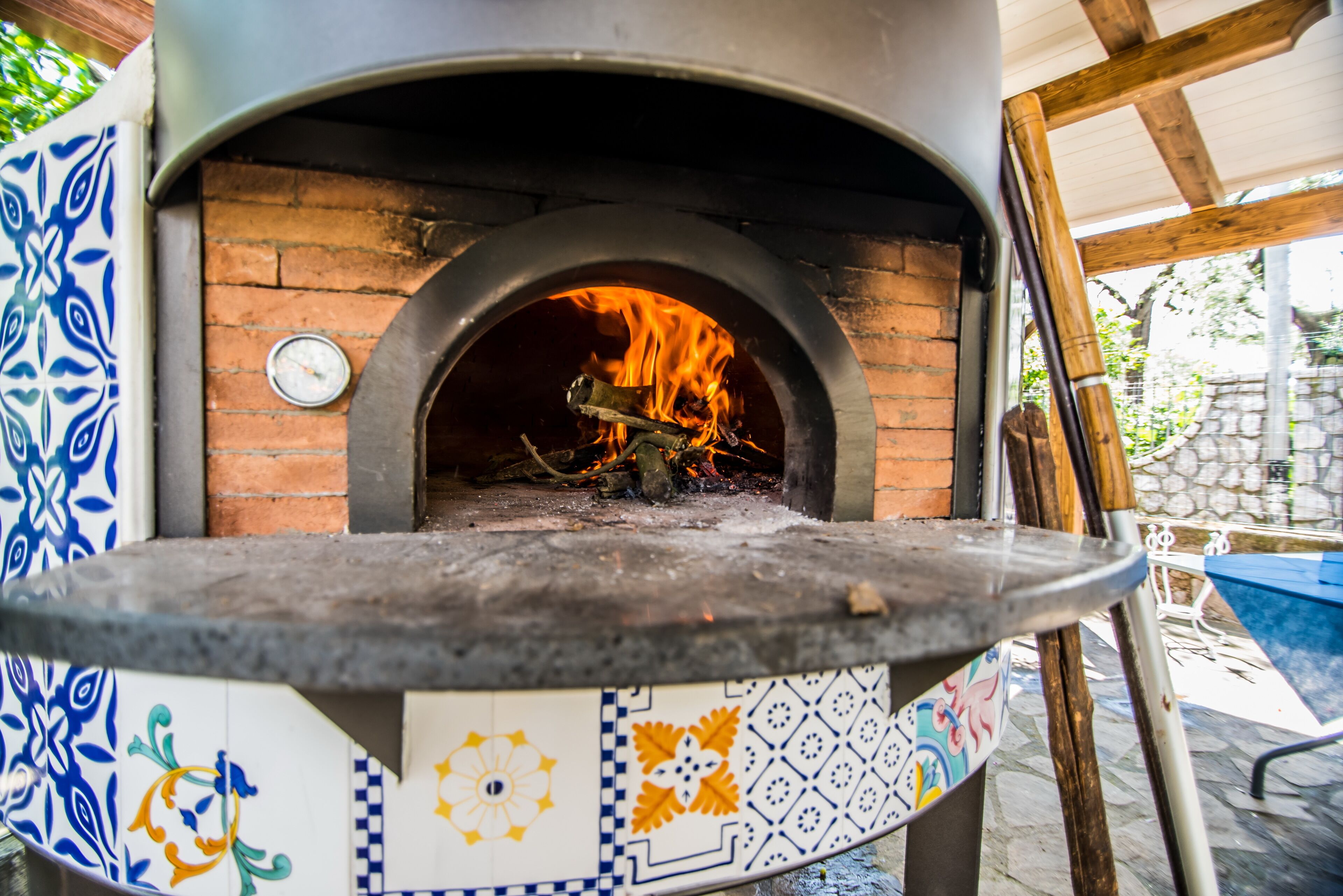 A traditional brick oven pizza oven with a decorative tile base.