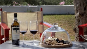 Une table avec une bouteille de vin, deux verres de vin rouge et un plateau de nourriture couvert, contenant du pain et du fromage.