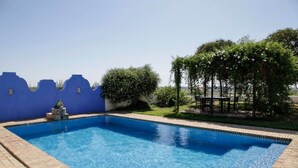 Une piscine rectangulaire bordée de carreaux, entourée d’un mur bleu orné d’un motif ondulé.