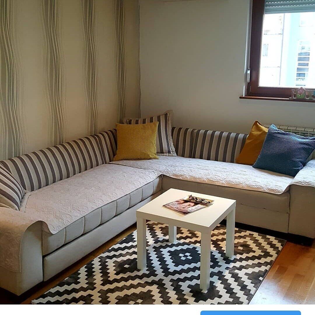 A living room with a sofa, a coffee table, and a patterned rug.