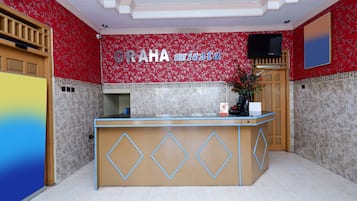 A reception desk with a floral wall design, a mounted television, and a wooden door.