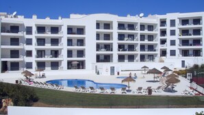 Un hôtel à plusieurs étages doté de balcons, d’une piscine et d’espaces de détente en plein air.