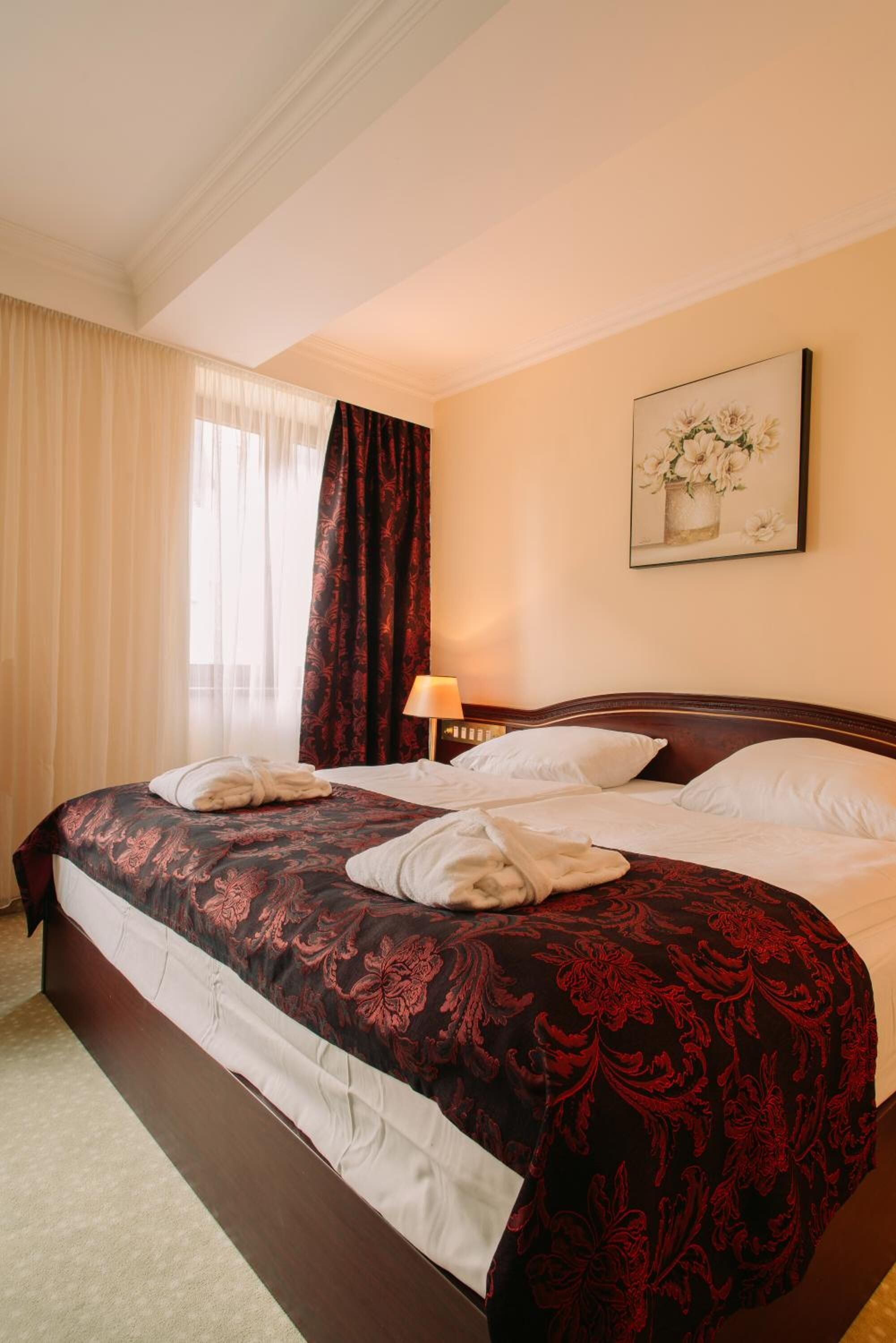 Una habitación de hotel con una cama grande, una mesita de noche, una lámpara y un cuadro en la pared.