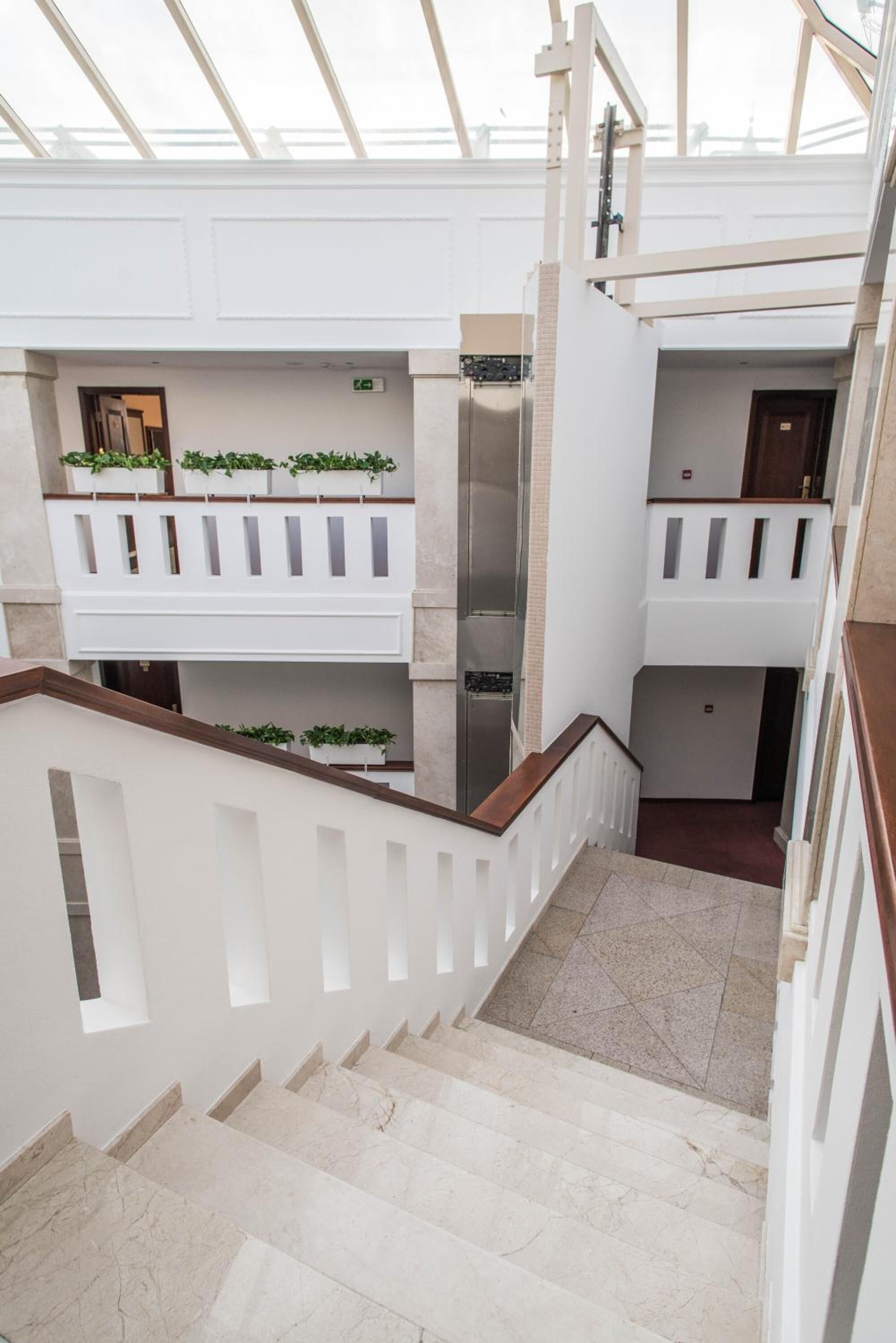 Un intérieur à plusieurs niveaux, avec un escalier, des murs blancs et un plafond en verre.