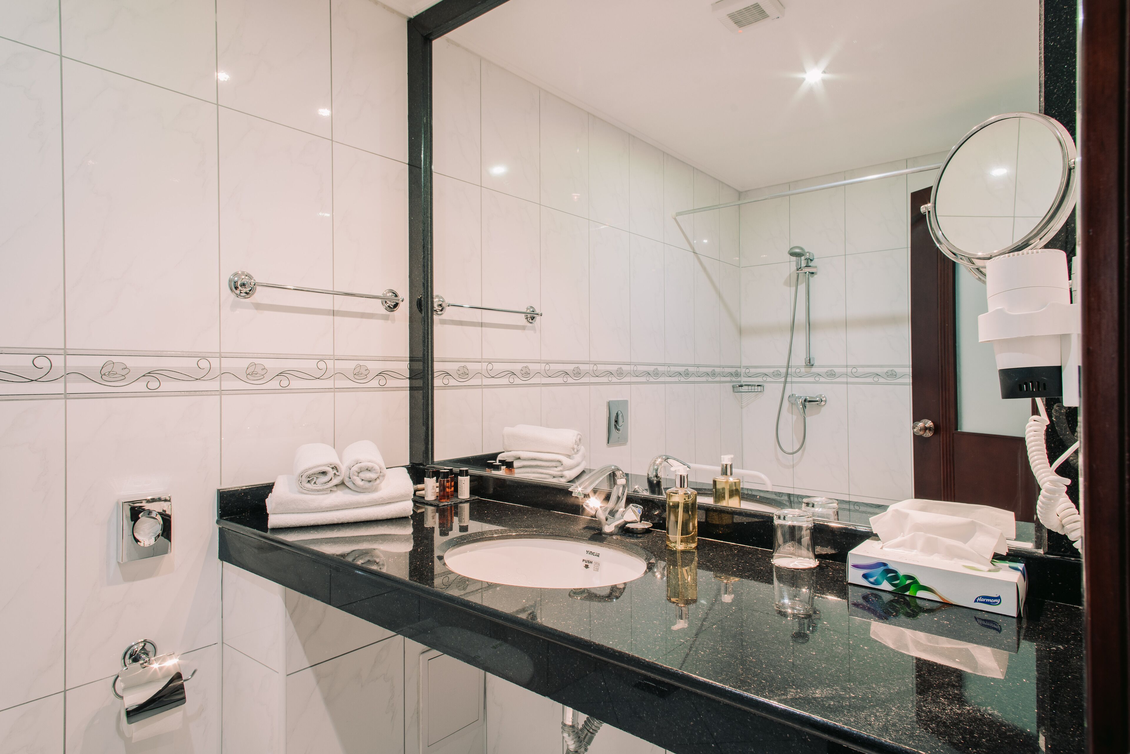 A modern bathroom with a black countertop, white sink, and a large mirror.