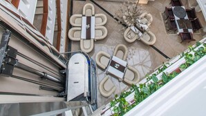 Un atrium à plusieurs niveaux doté d’un espace central aménagé en salon, de balcons ornés de plantes et d’une conception architecturale moderne.