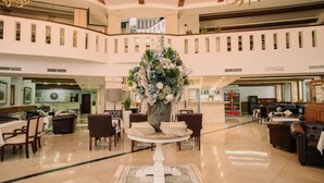 Un hall d’entrée spacieux agrémenté d’une composition florale centrale, de plusieurs espaces aménagés pour s’asseoir et d’un comptoir de réception.
