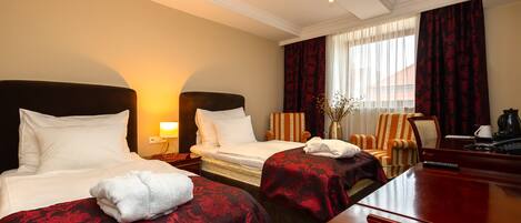 A hotel room with two beds, a desk, and a chair.