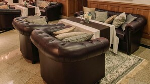 Un vaste espace de détente avec des canapés en cuir, une table basse et une table à manger pour quatre personnes.