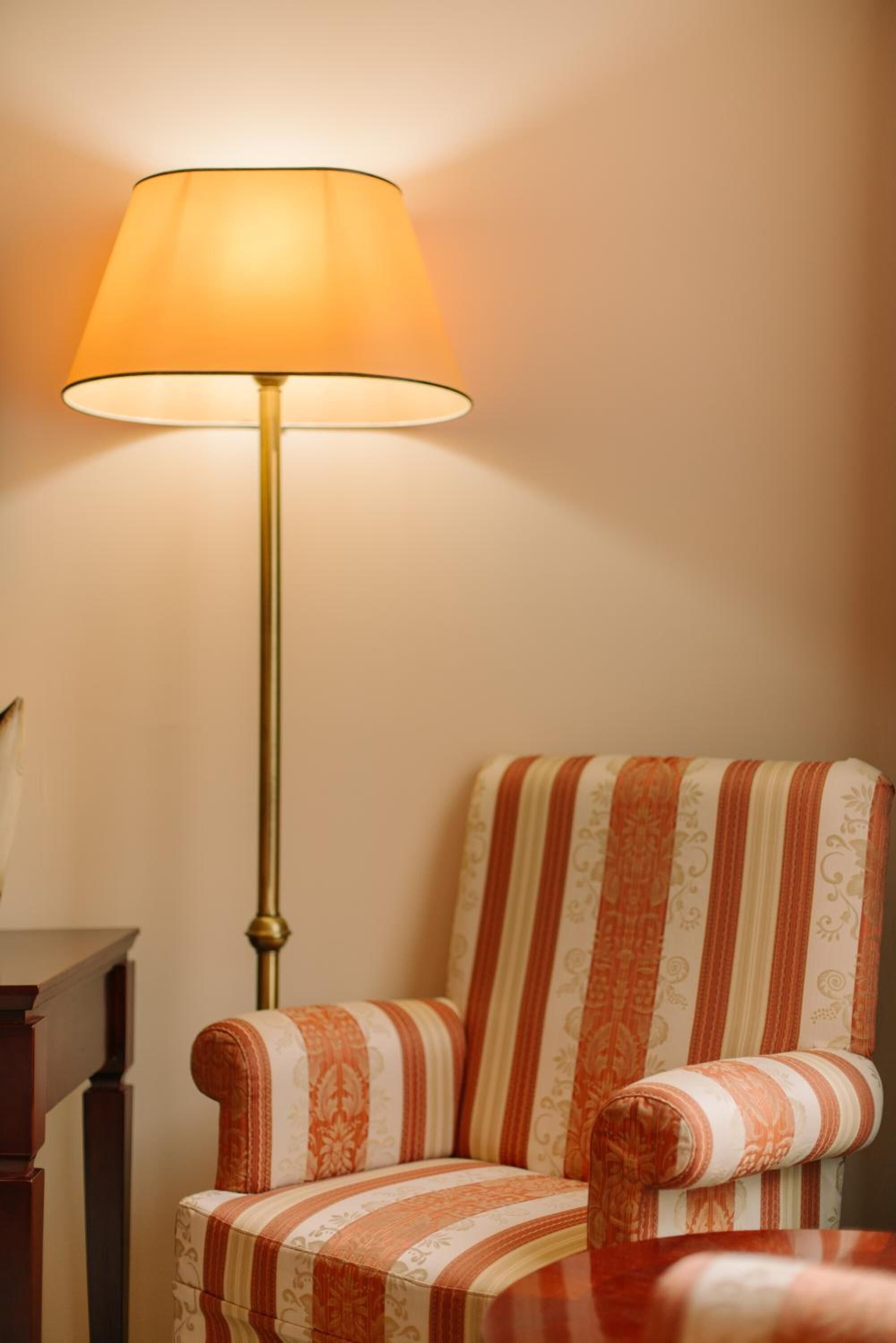 A striped armchair with a lamp beside it.