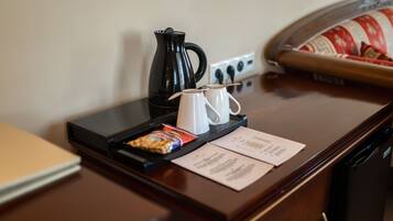 Un bureau dans une chambre d’hôtel, avec une machine à café, deux tasses, un plateau avec des en-cas et un menu.