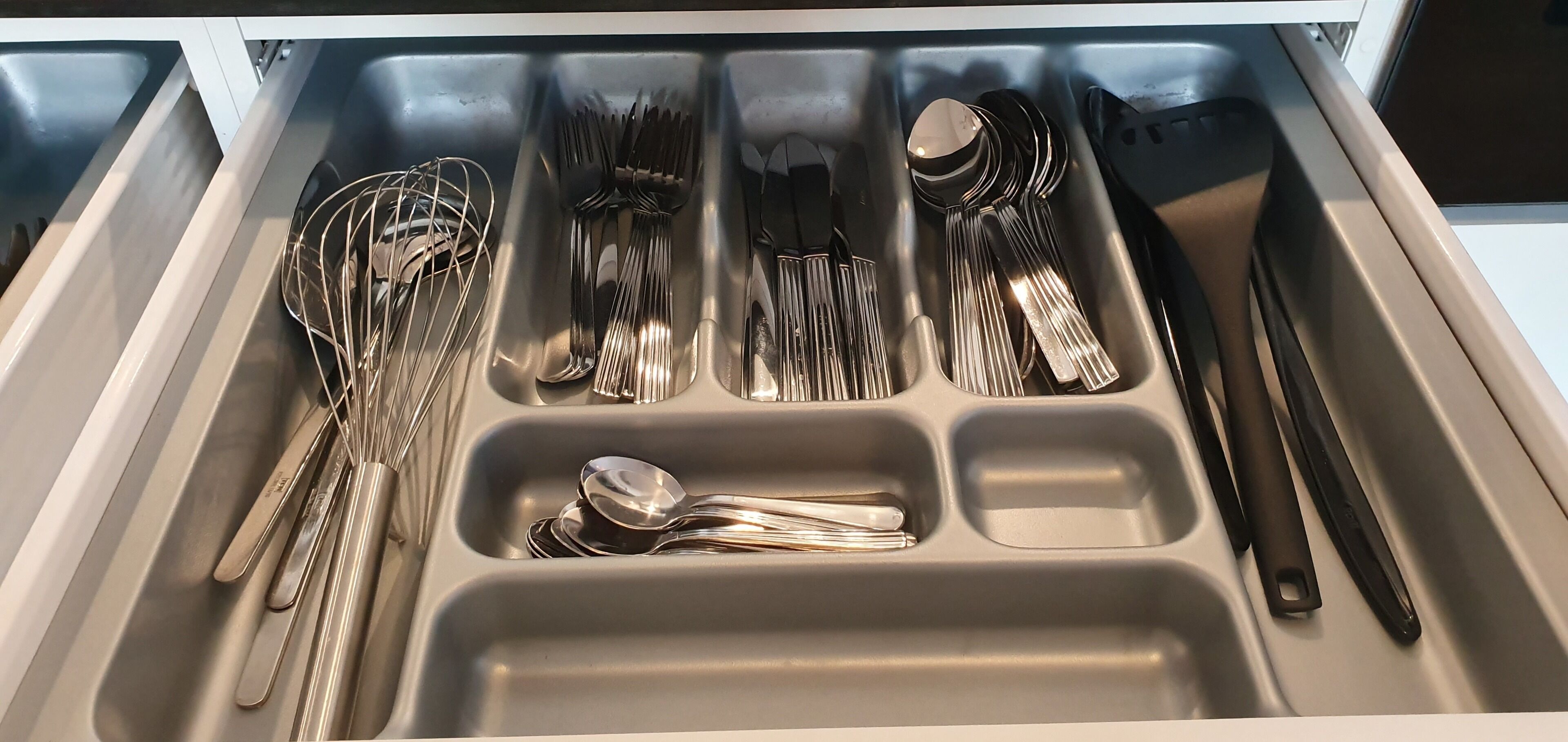 Un cajón con diversos utensilios de cocina, como tenedores, cucharas y cuchillos.