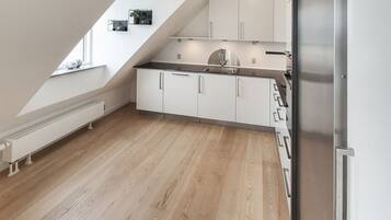 A modern kitchen with white cabinets, a stainless steel refrigerator, and a wooden floor.