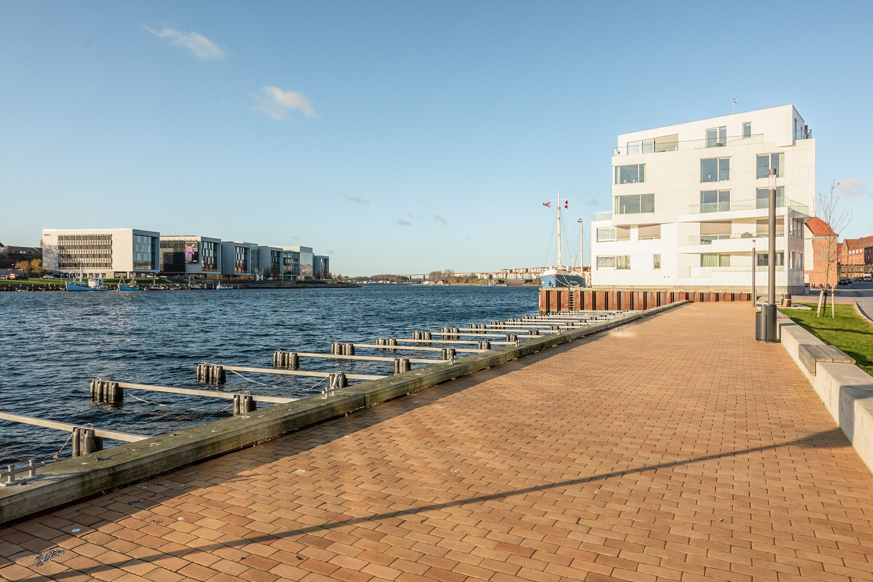 A waterfront walkway with a modern building and a dock.