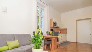 A modern living room with a grey sofa, a coffee table with a plant, and a dining area with a wooden table and chairs.