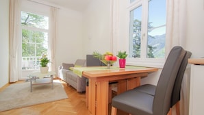 A dining area with a wooden table, chairs, and a view of mountains through large windows.