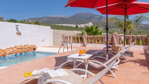 A poolside area with lounge chairs, a table with drinks, and a view of mountains. - Villa Sol Alozaina by Ruralidays (Málaga)