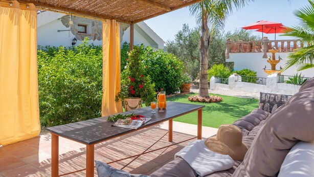 An outdoor seating area with a table, cushions, and a drink. - Villa Sol Alozaina by Ruralidays (Málaga)