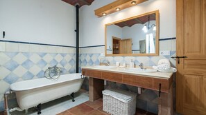 A bathroom with a bathtub, two sinks, a mirror, and a wooden door.