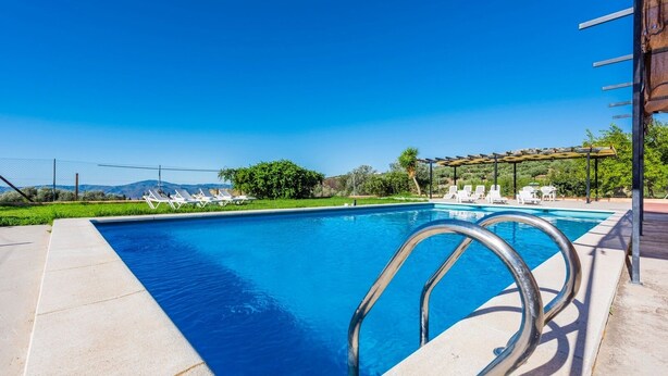 A rectangular swimming pool with a clear blue water, surrounded by a concrete deck. There are metal pool ladders on the right side and white lounge chairs along the pool's edge. - Casa Rural Azahar Periana by Ruralidays (Málaga)