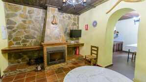 A stone fireplace with a television above it, a wooden chair, and a map on the table. - Casa Rural Azahar Periana by Ruralidays (Málaga)