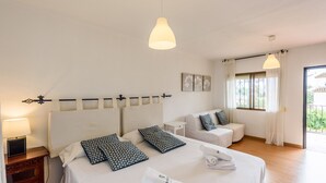 Ein Hotelzimmer mit zwei Betten, einem Sofa, einem Schreibtisch und einem Fenster mit Vorhängen.