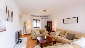 Ein Wohnzimmer mit einer Sofagarnitur, einem Couchtisch, einem Fernseher und einem Bücherregal.