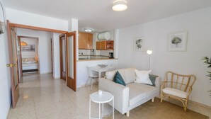 Um espaço compacto para viver, com cozinha compacta, sofá, cadeira e uma pequena mesa.