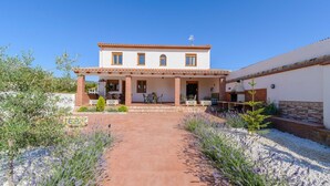 A two-story house with a patio, outdoor seating, and a barbecue area. - Casa Rural Embalse Bermejales Arenas del Rey by Ruralidays (Granada)