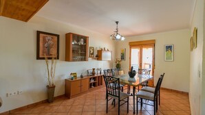 A dining area with a glass table, chairs, a cabinet with glass doors, and a chandelier. - Casa Rural Embalse Bermejales Arenas del Rey by Ruralidays (Granada)