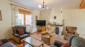 A living room with a fireplace, a television, and multiple seating options. - Casa Rural Embalse Bermejales Arenas del Rey by Ruralidays (Granada)