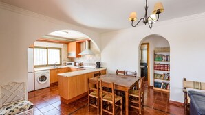 A compact kitchen with a central island, a dining area, and a bookshelf. - Casa Los Pérez Sedella by Ruralidays (Málaga)