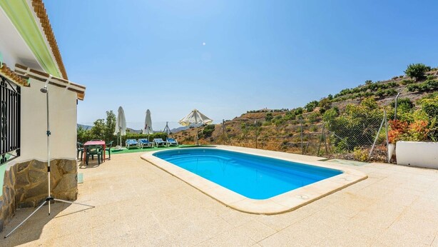 A rectangular swimming pool with a tiled deck, surrounded by a fence and greenery. - Casa Los Pérez Sedella by Ruralidays (Málaga)
