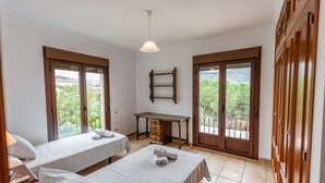Une chambre avec deux lits, un bureau et un balcon offrant une vue.