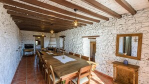 Un comedor rústico con una larga mesa de madera, paredes de piedra y vigas de madera a la vista.
